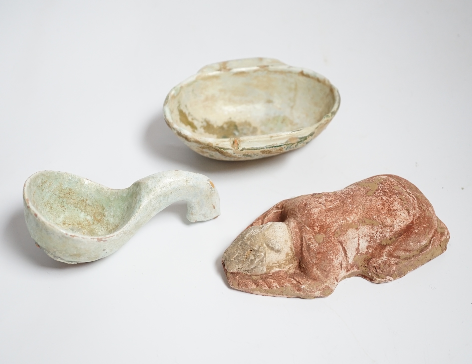 A Chinese glazed pottery ‘ear’ cup and similar spoon, Han dynasty, and a pottery figure, Song dynasty, largest 13cm wide